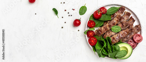 Baked minced meat wrapped in bacon with spinach, avocado and cherry tomato, Healthy fats, clean eating for weight loss. Keto paleo diet menu. top view