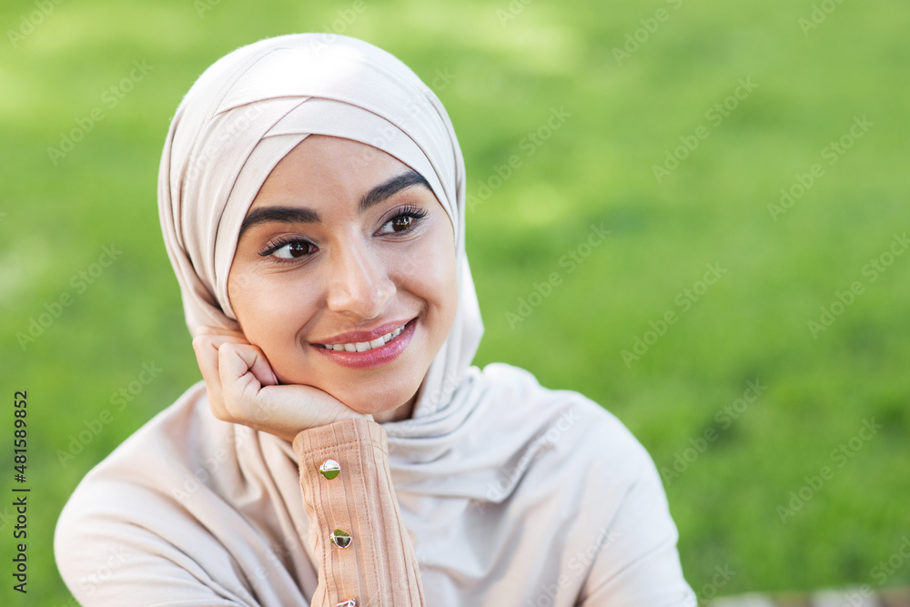 Portrait of smiling pensive pretty young arab muslim woman in hijab, looking at empty space Portrait of smiling pensive pretty young arab muslim woman in hijab, looking at empty space