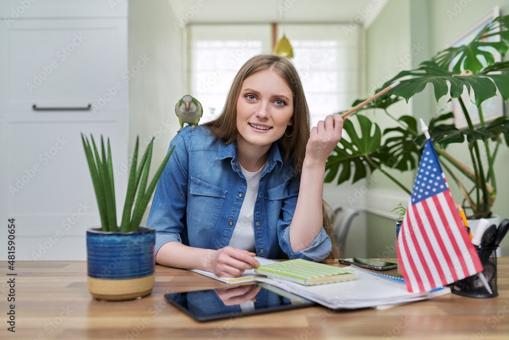 Young female student looking at the camera, USA flag on the table. Young female student looking at the camera, USA flag on the table.