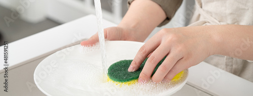 Fotografie Woman housewife is doing the dishes at home kitchen.