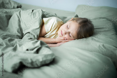 A little girl lies in bed and is sick, feeling unwell and having a cold in the winter