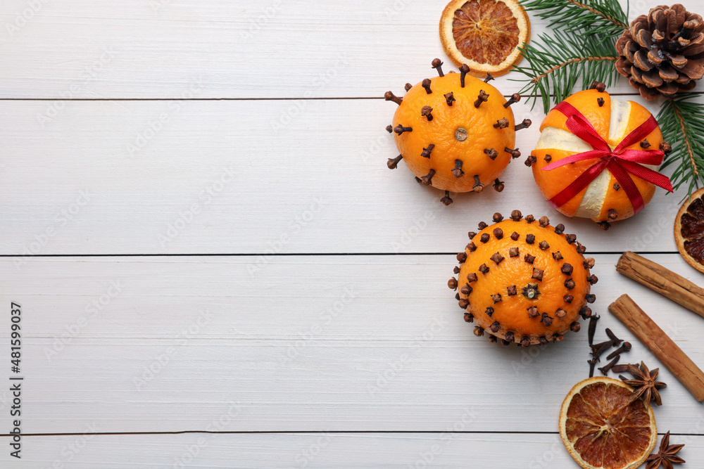 Pomander balls made of tangerines with cloves, spices and fir branches on white wooden table, flat lay. Space for text Pomander balls made of tangerines with cloves, spices and fir branches on white wooden table, flat lay. Space for text