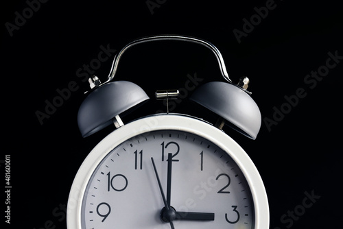 Time concept. White alarm clock in dark background with copy space.