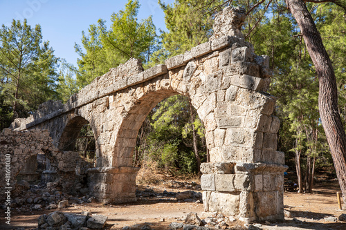 Ruins of the aqueduct of the ancient ancient city of Phaselis illuminated by the bright sun in Pine forest, woods in sunny weather in Turkey, Antalya, Kemer. Turkey national nature landmarks. © Suzi