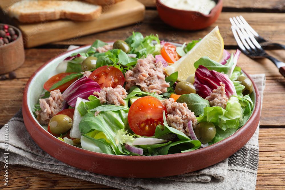 Plate of delicious salad with canned tuna and vegetables served on wooden table Plate of delicious salad with canned tuna and vegetables served on wooden table
