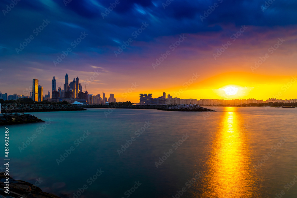 Dramatic sunset sky with clouds. Beautiful sunset over the Arabian sea in Dubai Marina UAE. Nature and beauty concept. Orange sundown. Long Exposure Shot.