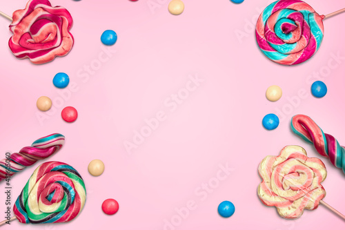 colorful candies and candy bars on pink background with copyspace blank area