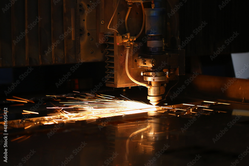 Sparks fly out of automated machine, metal processing laser on metallurgical background