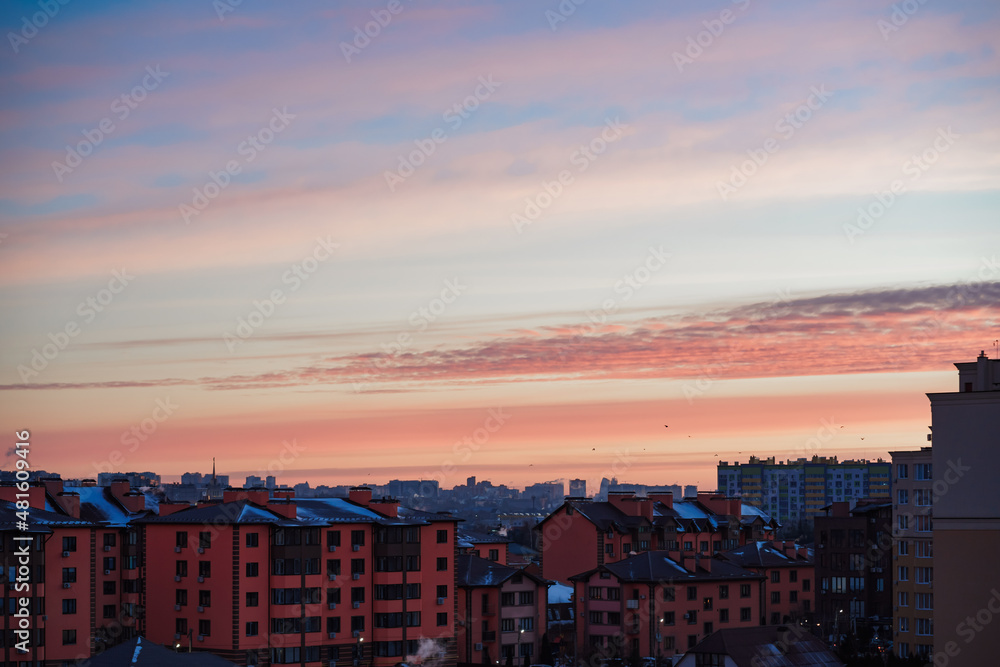 Fototapeta premium view of the city at dawn. blue smoke comes out of the chimney. pink sky 