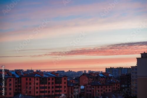 view of the city at dawn. blue smoke comes out of the chimney. pink sky 