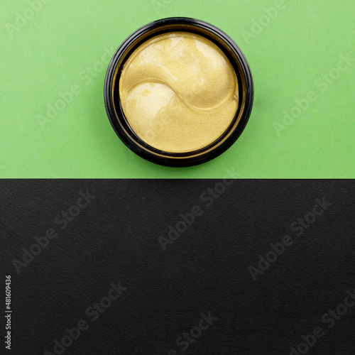 cosmetic golden hydrogel patches for moisturizing and nourishing the skin under the eyes on green background. Skin care, wellness and spa concept, mockup with copy space