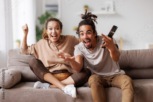 Overjoyed young african american couple celebrating goal while watching football match together photo