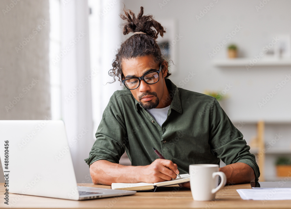 Young african american man freelancer working remotely on laptop or studying online at home Young african american man freelancer working remotely on laptop or studying online at home