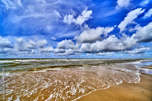 the north sea beach with clouds and sun , wide angle view of the nordsea. photo