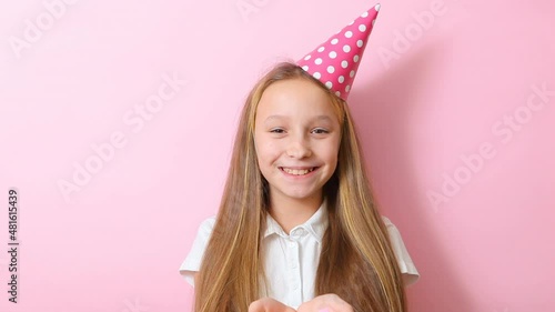 teenage girl in a festive cap throws up confetti on colored background close-up