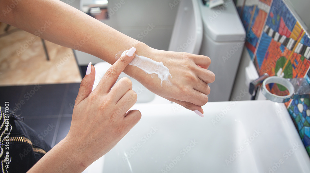 Fototapeta premium Female hands holding body cream in bathroom.