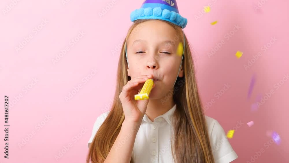 a teenage girl in a festive cap blows a tune. Birthday concept a teenage girl in a festive cap blows a tune. Birthday concept