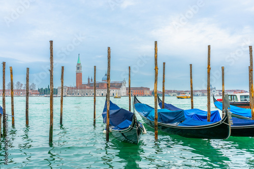 December 2, 2021 - Venice, Italy: Gondolas moored at Sam Marco Gondola Service Station on Grand Canal with Chiesa di San Giorgio Maggiore on the background. © Антонина Тадеуш