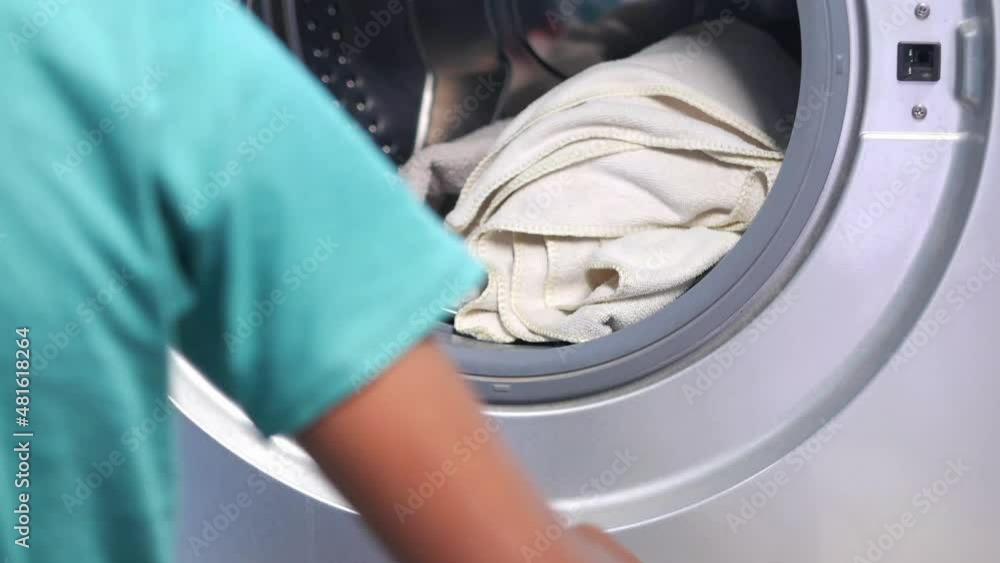 man putting shirt into washing machine. man putting shirt into washing machine.