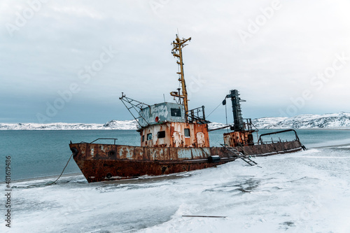 An old abandoned ship on the shore of the Barents Sea in the Arctic Ocean. The village of Teriberka Kola peninsula. The destroyed economy and industry of Russia concept photo