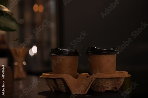 Fototapeta Naklejka Na Ścianę i Meble -  Takeaway coffee cups with cardboard holder on wooden table indoors