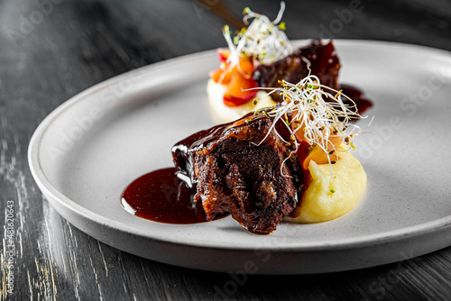 Stewed veal cheeks with mashed potatoes on plate on wooden table  photo