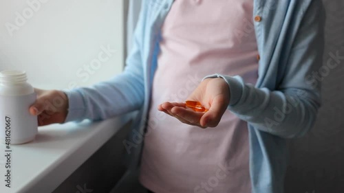 Teenage girl takes omega 3 capsules in the interior of the room