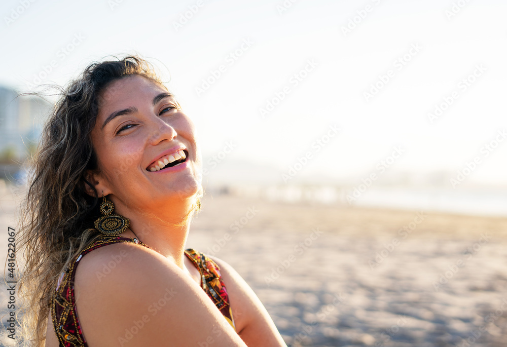 young latin woman sitting on the the beach smiling happy portrait young latin woman sitting on the the beach smiling happy portrait