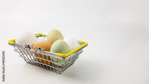 chicken eggs of natural shades are multicolored in a basket from a supermarket on a light background. chickens lay colored eggs. purchase of products for Easter photo