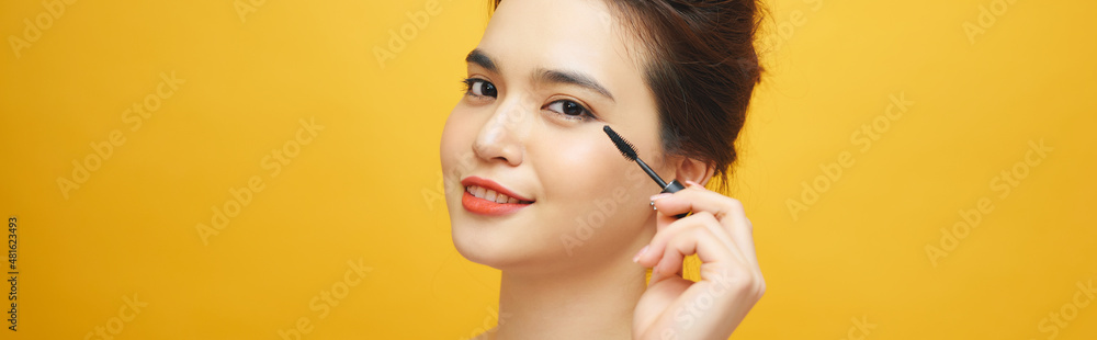 Women who make up makeup, eyelashes, mascara on yellow background Women who make up makeup, eyelashes, mascara on yellow background