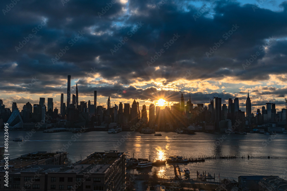 sunset over the river, Manhattan silhouette skyline with stuning sun ray,  wide angle perspective.