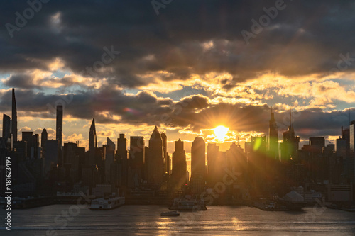 Vivid sunrise over Manhattan skyline with illuminated clouds above the buildings. photo