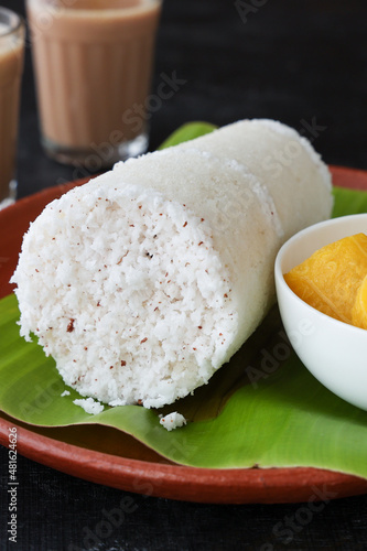 Popular South Indian breakfast puttu / pittu made of rice flour and coconut with banana and kadala curry, Kerala breakfast, India. Bamboo puttu prepared in steam 