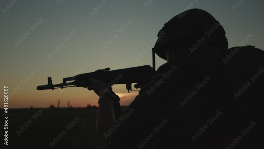 Infantryman in helmet with rifle aiming at hostile forces at sunset on field. Infantryman in helmet with rifle aiming at hostile forces at sunset on field.