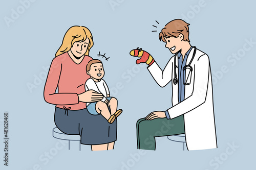 Pediatrician working with babies concept. Young smiling man pediatrician sitting and playing with small baby on mothers knees with mitten vector illustration 