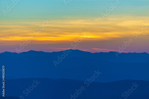Sunrise or sunset evening time over the mountains and forest with red or orange clouds sky.