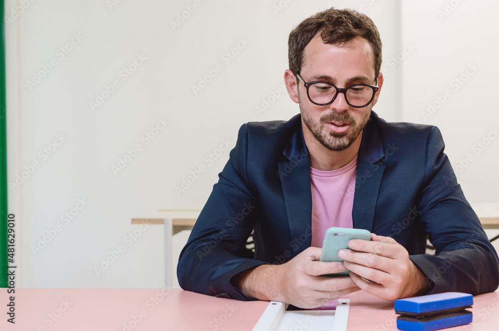 bearded adult man smiling and using phone in an office bearded adult man smiling and using phone in an office