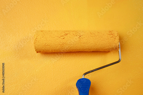 Roller Brush Painting, Worker painting on surface wall  Painting apartment, renovating with yellow color  paint. Leave empty copy space white to write descriptive text beside.