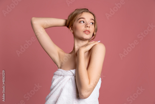 Half-length portrait of young beautiful slim girl in white towel posing isolated over pink studio background. Natural beauty concept.