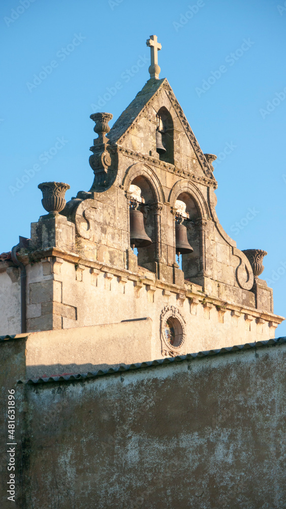Campanario de iglesia medieval tras muro de piedra