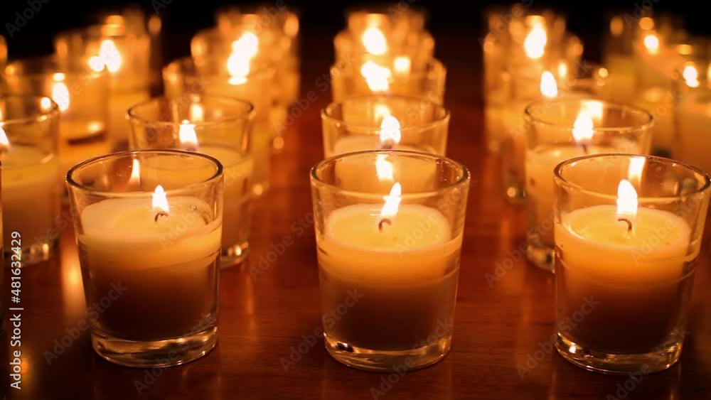 Camera moves past rows of glowing candles in a church or temple. Camera moves past rows of glowing candles in a church or temple.