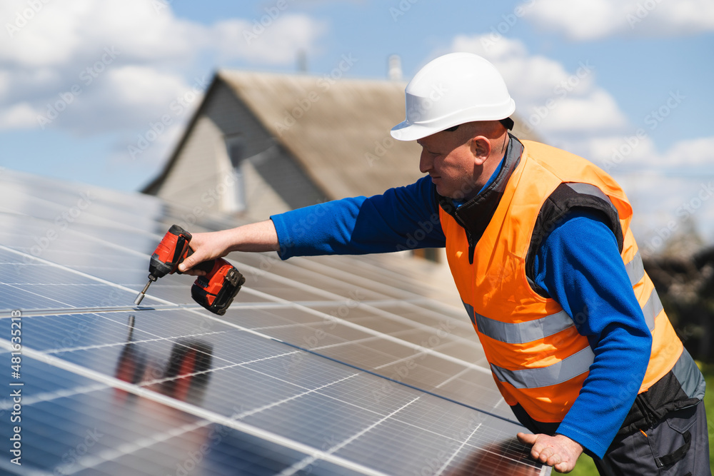 Man with drill screwdriver installs panels at a solar power plant Man with drill screwdriver installs panels at a solar power plant