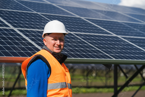 Portrait of male electrical engineer on the background of solar panels at a power plant