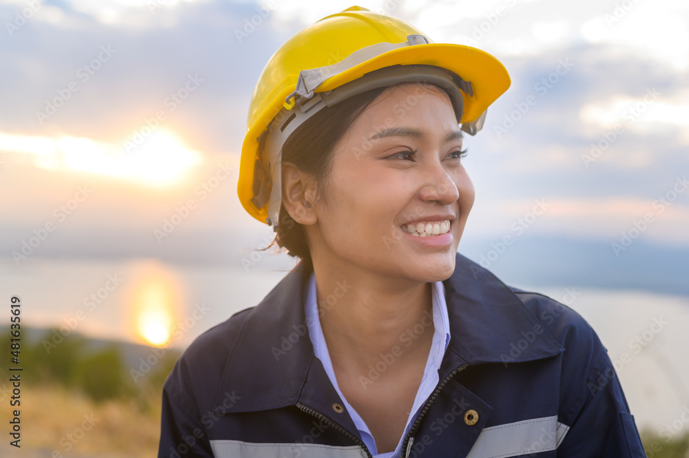 a woman engineer is putting a protective helmet on her head at sunset. a woman engineer is putting a protective helmet on her head at sunset.