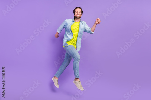 Full size photo of jumping smiling guy running fast speed traveling enjoy free time isolated on violet color background © deagreez