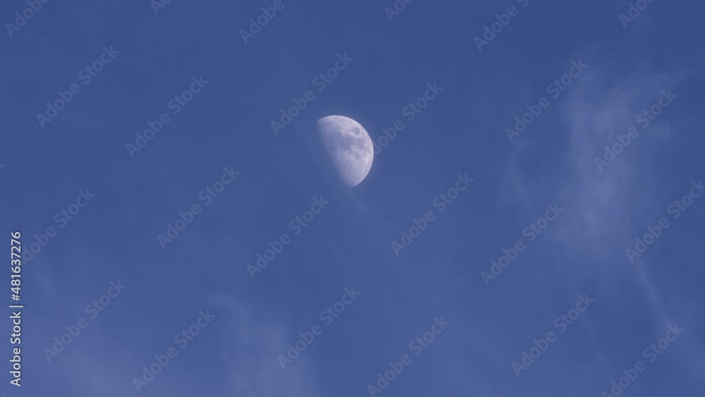 Time lapse of wispy clouds moving across the sky with the waxing first quarter moon in the blue sky Time lapse of wispy clouds moving across the sky with the waxing first quarter moon in the blue sky