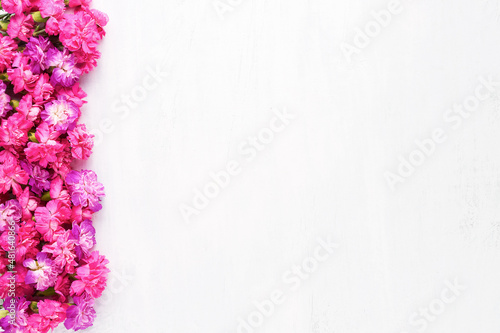 Pink carnations flowers border on a white wooden background. Top view, copy space