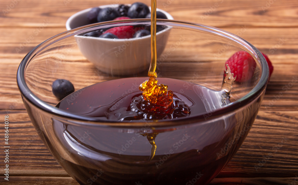 Honey pouring with some berries on the background Honey pouring with some berries on the background