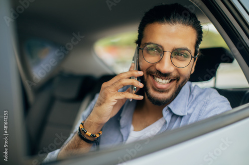 Closeup of cheerful man sitting in taxi, talking on phone © Prostock-studio