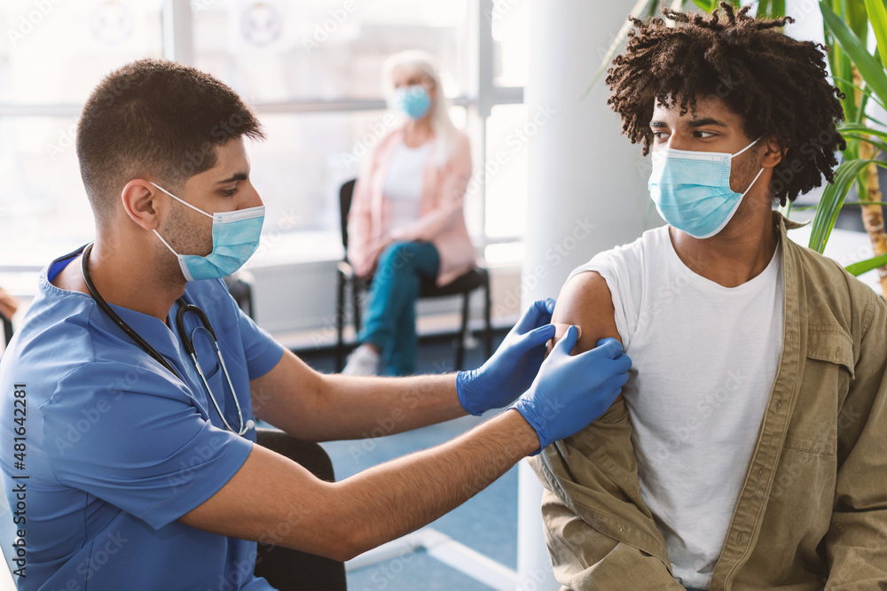 Fototapeta premium Black Guy Getting Vaccinated Against Covid-19, Doctor Applying Sticking Plaster